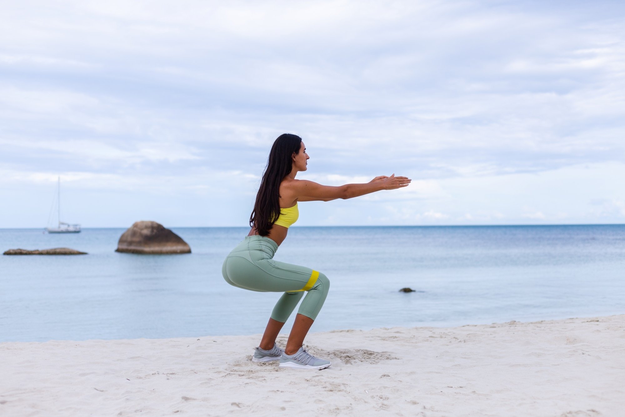 Mujer atractiva realizando ejercicio en la playa para fortalecer el cuerpo
