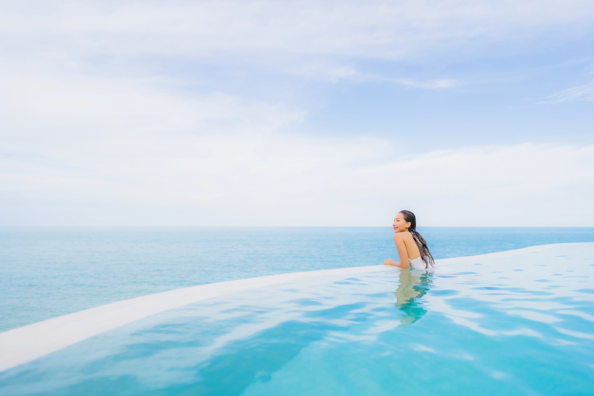 Mujer joven disfrutando de alberca infinity con una vista panoramica al mar