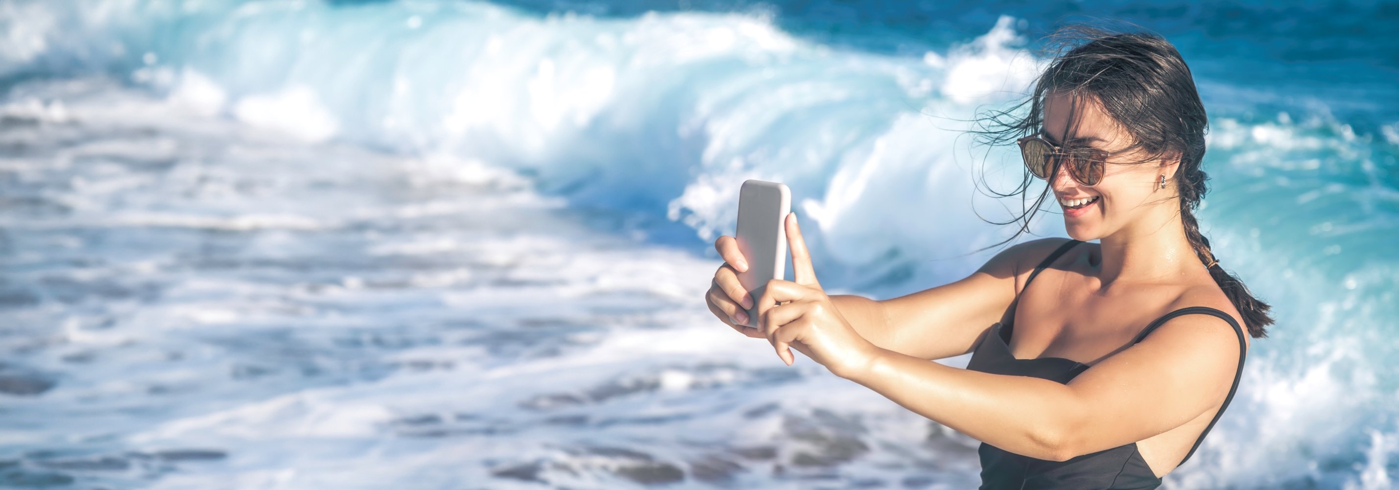 Mujer tomandose una selfie con el mar de fondo para embellecer una postal