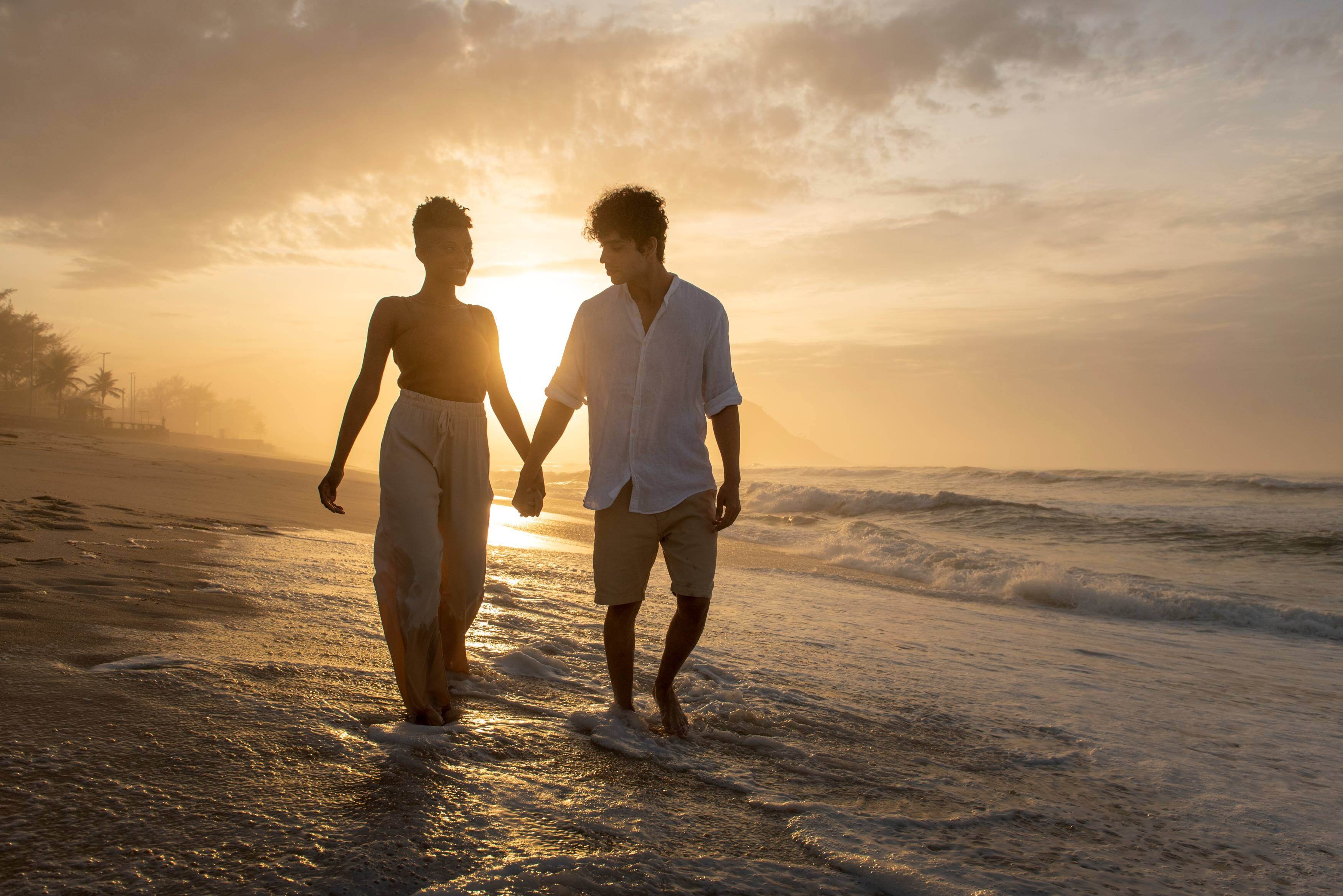 Pareja disfrutando de una caminata al atrdecer por la playa