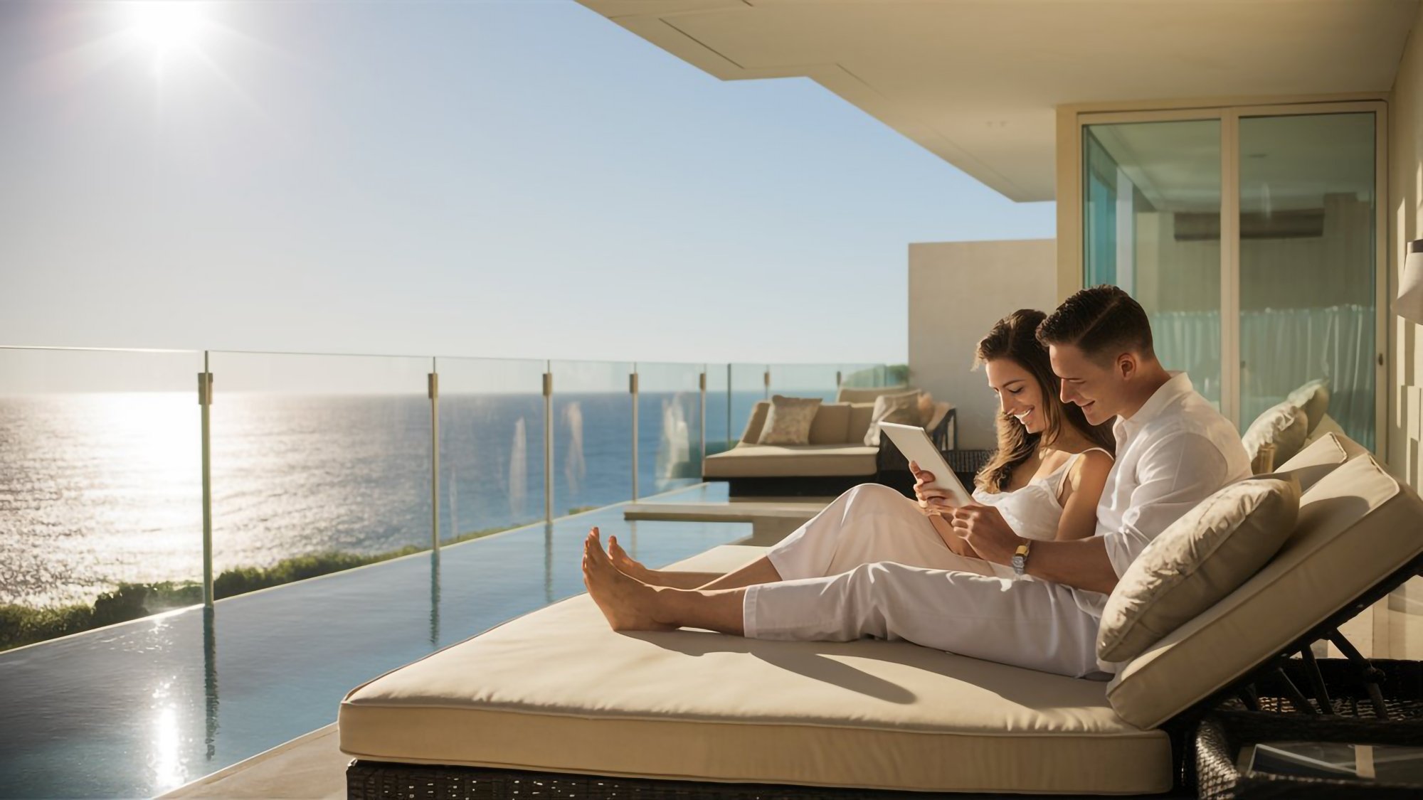 Pareja disfrutando la lectura de un libro en la terraza del departamento con vista al mar