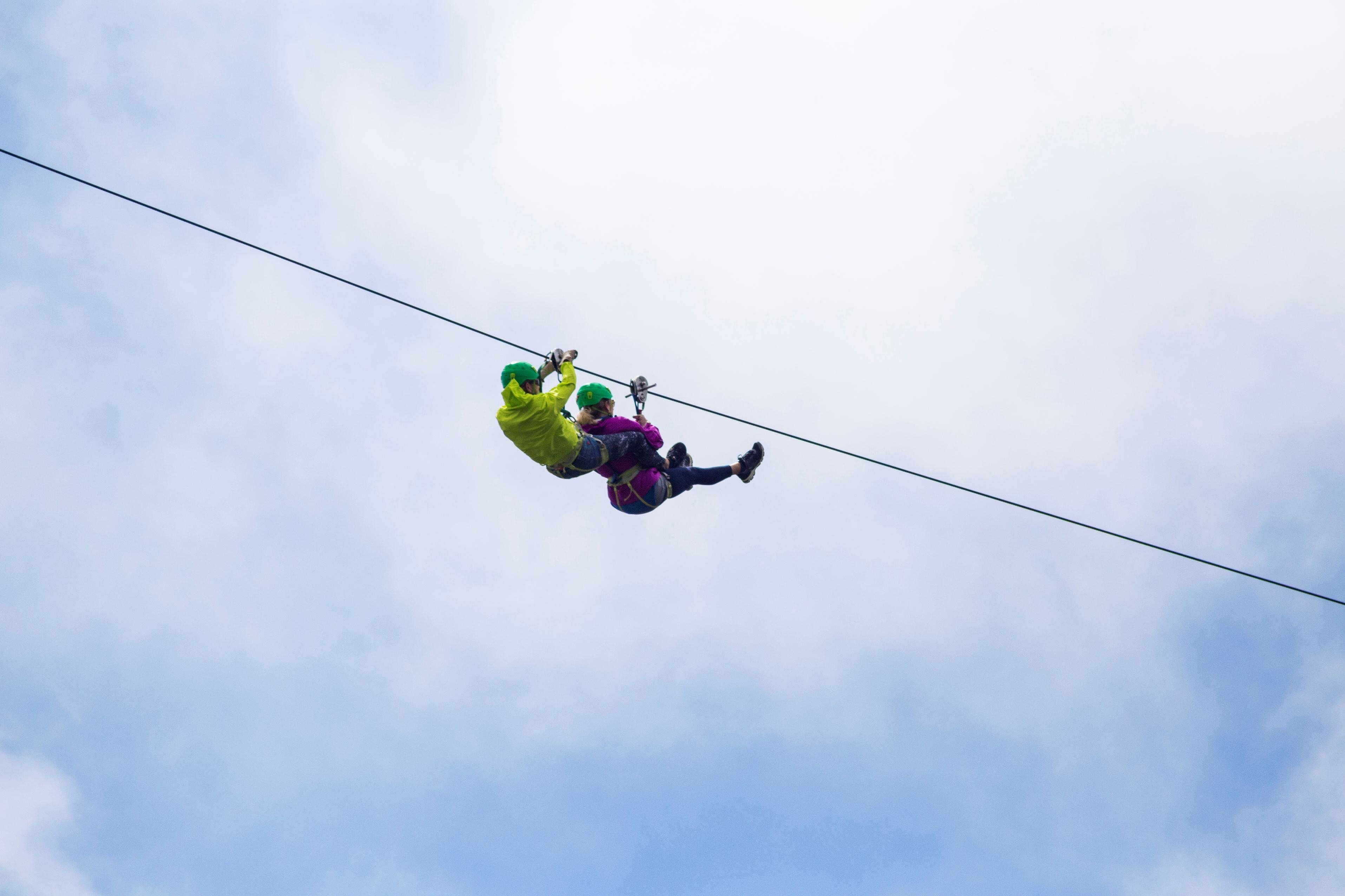 adventurous-tourist-zip-lining-against-cloudy-sky